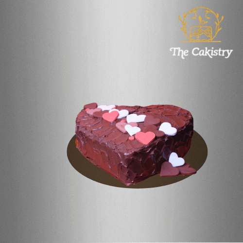 Heart-shaped cake with red and white hearts, featuring 'The Cakistry' logo.